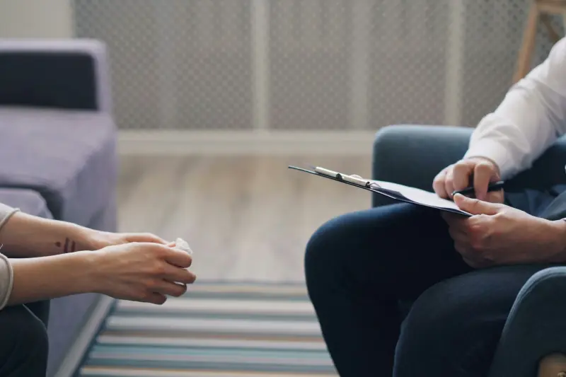 Een adviseur met een klembord in gesprek met een bewoner