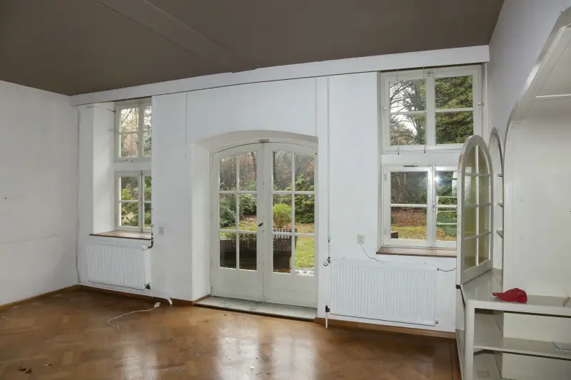 Een lege kamer met openslaande deuren naar de tuin